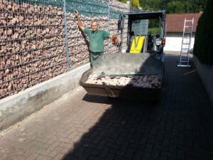 Ein moderner, dekorativer Gabionen-Zaun aus mit Steinen gefüllten Drahtkörben als Sichtschutz und Grundstücksbegrenzung in Baden-Baden